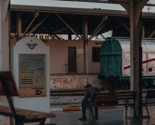 Ein Mann sitzt allein auf einer Bank am Bahnsteig und wartet — das Bild des Wochenend-Vaters zwischen zwei Leben